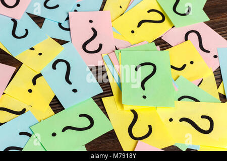 Pile of colorful paper notes with question marks on wooden background. Closeup. Stock Photo