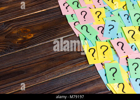 Just a lot of question marks on colored papers on wood background. Stock Photo