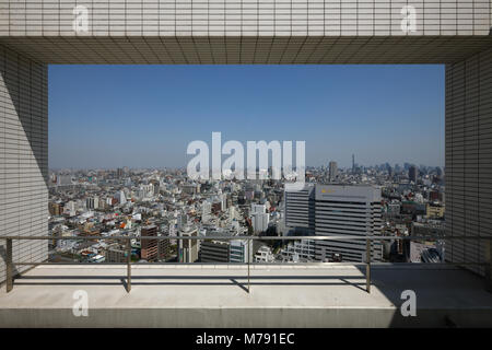 View on an ocean of houses in Tokyo. Taken from a skyscraper in Shinjuku through a hole in the facade. View is half blue sky half cityscape. Stock Photo