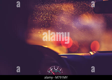 On the road on a rainy night, rain drops on the windshield limit the visibility of the road, blurred lights of urban traffic jams, rainy nighttime on  Stock Photo