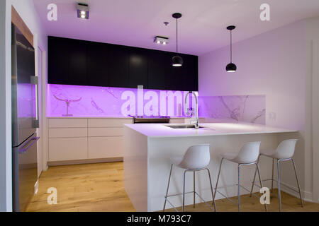 Black and white kitchen with island and stools and a purple lightning Stock Photo