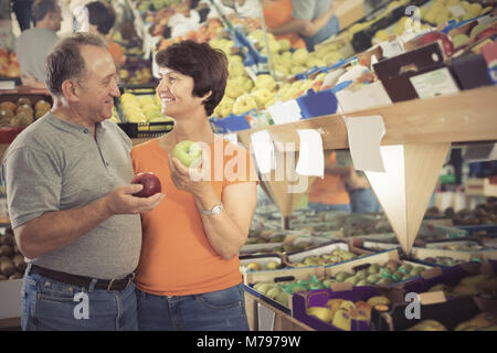 Man And Woman Are Choosing Colorful Apples In The Fruit Store Stock 