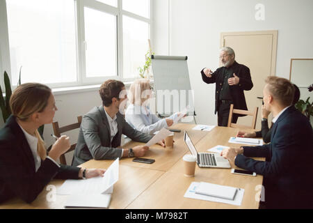 Senior coach giving presentation to executive managers team in b Stock Photo