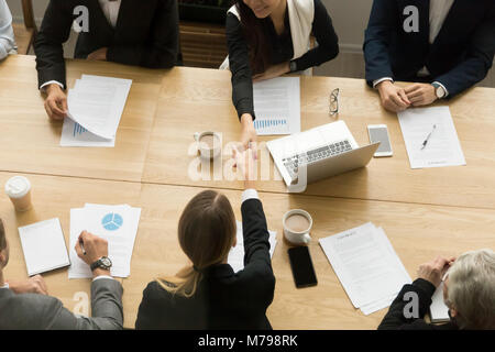 Two businesswomen shaking hands at group meeting, top view Stock Photo