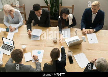 Asian and caucasian businesswomen handshaking at group meeting,  Stock Photo