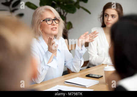 Aged businesswoman, teacher or business coach speaking to young  Stock Photo
