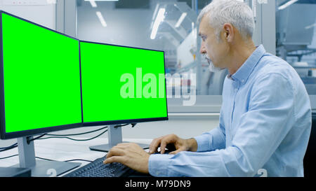 Engineer Working on a Computer with Two Displays, One has Chroma Key Great for Mockup Template and other Component in CAD Program. Stock Photo