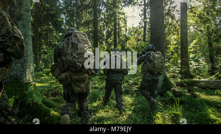 Squad of Five Fully Equipped Soldiers in Camouflage on Reconnaissance Military Mission, Rifles Ready. They're Moving in Formation Through Dense Forest Stock Photo
