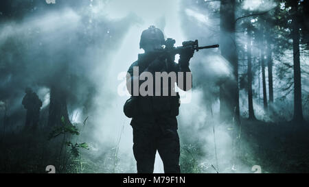 Silhouette of the Fully Equipped Soldier Moving Through Smokey Forest with Rifle Ready To Shoot. Reconnaissance Military Operation. Squad is Moving. Stock Photo