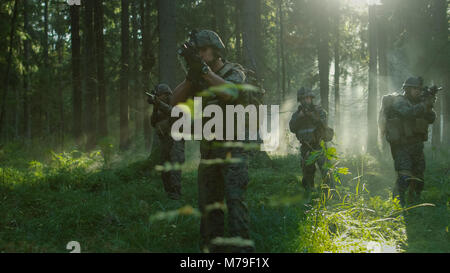 Five Fully Armed Soldiers Stand Alert with Guns Ready. Military Operations Takes Place in the Sunny Dense Forest. Stock Photo