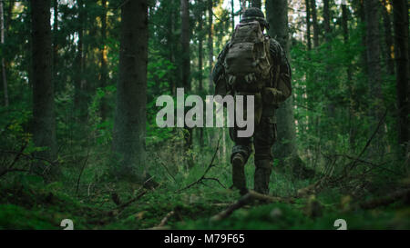 Shot of a Fully Equipped Soldier Moving Further in the Dense Forest. He's on the Reconnaisance Military Mission. Low Angle Footage. Stock Photo