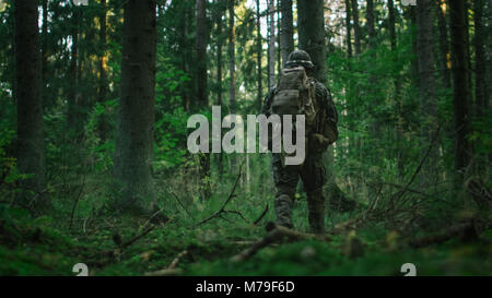 Shot of a Fully Equipped Soldier Moving Further in the Dense Forest. He ...