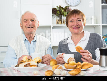 Smiling elderly couple having breakfast and talking at table at home Stock Photo