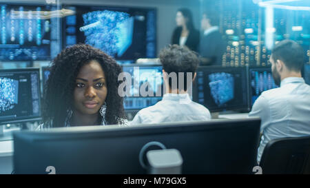 Female Computer Engineer Works on a Neural Network/ Artificial Intelligence Project with Her Multi-Ethnic Team of Specialist. Office is Multi ethnic Stock Photo