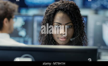Female Customer Service Representative Answer Client's Questions in a Headset. He Works for a Big Technological Company. Office Has Multi-Ethnic Team Stock Photo