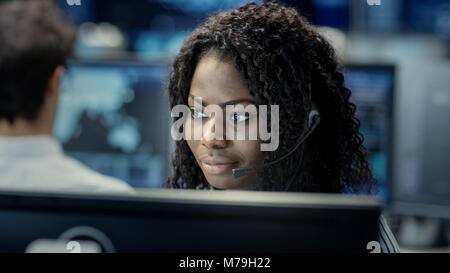 Female Customer Service Representative Answer Client's Questions in a Headset. He Works for a Big Technological Company. Office Has Multi-Ethnic Team Stock Photo