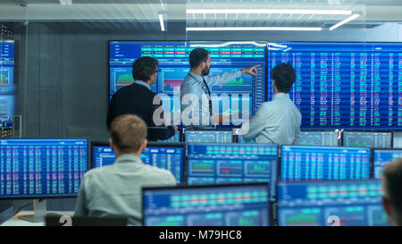 Three Experienced Stock Traders Talking Business, Consulting Documents and Argue About Data. They Work for a Big Stock Exchange Firm. Modern Office. Stock Photo