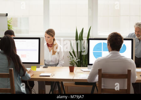 Business people working on computers sharing office desk in cowo Stock Photo