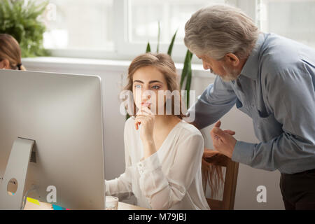 Senior mentor teaching young female intern using computer in off Stock Photo