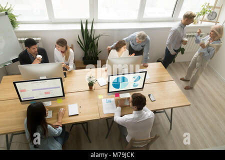 Diverse young and senior office workers collaborating talking, t Stock Photo