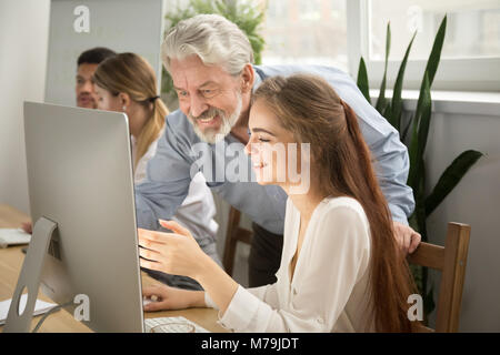 Smiling senior mentor supporting young intern showing good work  Stock Photo