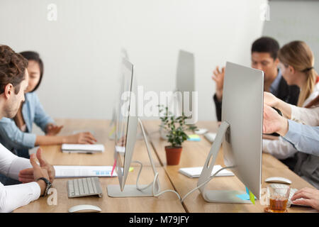 Office employees working on computers in coworking, desk with mo Stock Photo
