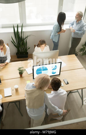 Senior and young employees working in office, top vertical view Stock Photo