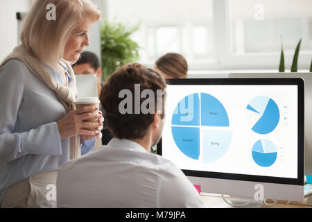 Senior executive checking annual report on computer screen helpi Stock Photo