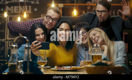 In the Bar/ Restaurant Hispanic Woman Takes Selfie of Herself and Her Best Friends. Group Beautiful Young People in Stylish Establishment. Stock Photo