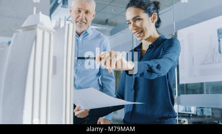 Two Professional Male and Female Architectural Engineers Work with Blueprints and on a Building Model Design for the Urban Planning Project. Stock Photo