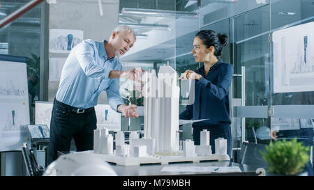 Two Professional Male and Female Architectural Engineers Work with Blueprints and on a Building Model Design for the Urban Planning Project. Stock Photo