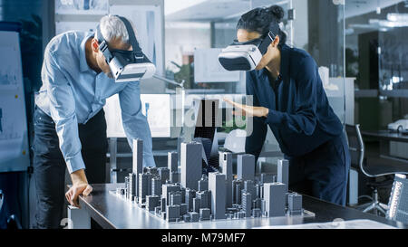 Male and Female Architects Wearing  Augmented Reality Headsets Work with 3D City Model. High Tech Office Professional People Use Virtual Reality Model Stock Photo