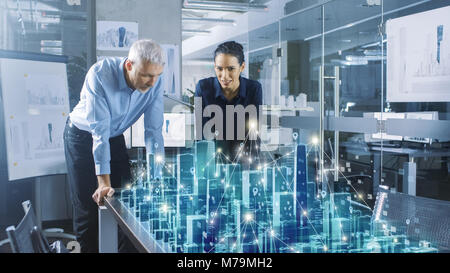 Male and Female Architects Work with Holographic Augmented Reality 3D City Model. Technologically Advanced Office Professional People Use VR Helmet Stock Photo