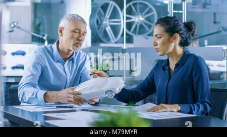 Experienced Automotive Designer and Female Engineer Works with a Concept Car Prototype Model, Perfecting it and Making Design Corrections. Stock Photo