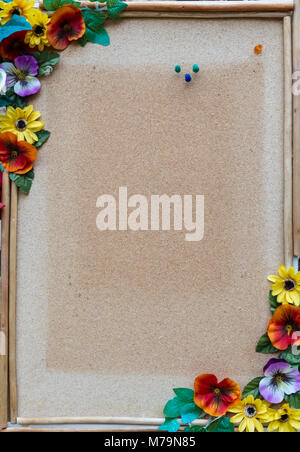 empty cork board with wooden frame and colorful flowers on the edges Stock Photo