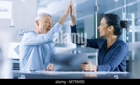 Senior Executive and Young Female Manager Working on a Laptop Win Big and Have Successful Moment, They High Five Each other and are Happy. Stock Photo