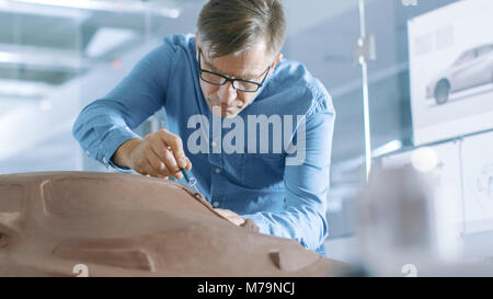 Experience Automotive Designer with a Rake Sculpts Prototype Car Model from Plasticine Clay. He Works in a Modern Studio in a Major Automotive Company Stock Photo