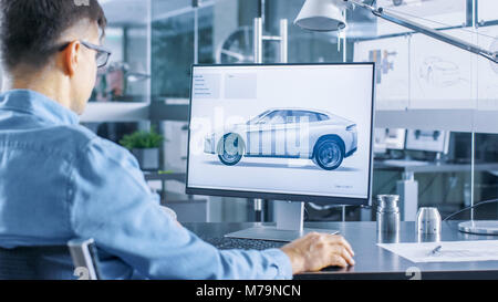 Automotive Engineer Works on the Personal Computer, He Perfects New Car Model Prototype Sketch. He Works in the Bright and Modern Office. Stock Photo