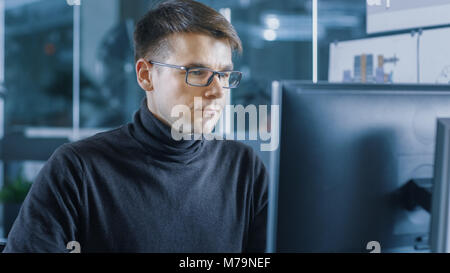 Young Male Industrial Engineer Works on a Personal Computer. Handsome Smart Man in the Bright Modern Office. Stock Photo