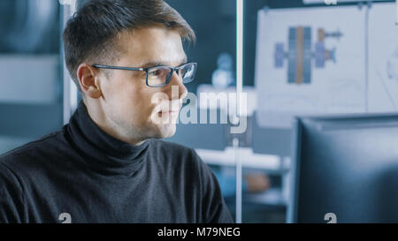 Young Male Industrial Engineer Works on a Personal Computer. Handsome Smart Man in the Bright Modern Office. Stock Photo