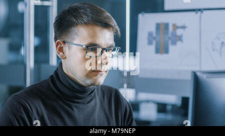 Young Male Industrial Engineer Works on a Personal Computer. Handsome Smart Man in the Bright Modern Office. Stock Photo