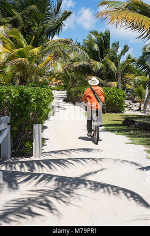 A man bicycling on a sandy path in San Pedro, Belize on the island of Ambergris. Stock Photo