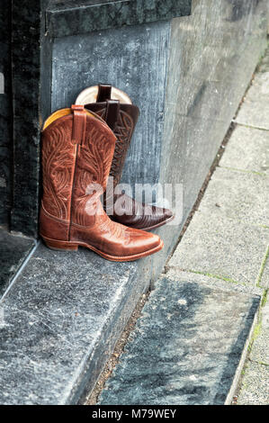 pair of leather cowboy boots standing on a side walk Stock Photo