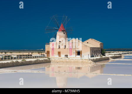 The salt museum with a windmill with reflection in the salt pans at the salina of Mozia at the west coast of Sicily between Trapani and Marsala. Stock Photo
