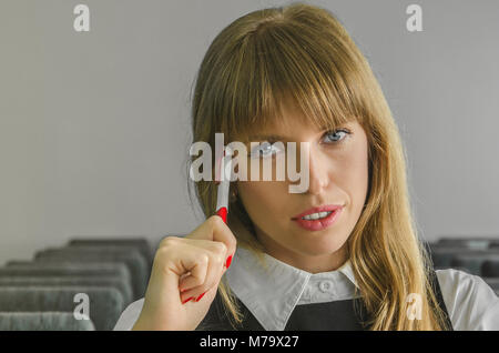 A beautiful business woman sitting alone in an auditorium. The girl sits in an empty lecture hall with a pan in your hand. Stock Photo