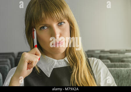 A beautiful business woman sitting alone in an auditorium. The girl sits in an empty lecture hall with a pan in your hand. Stock Photo