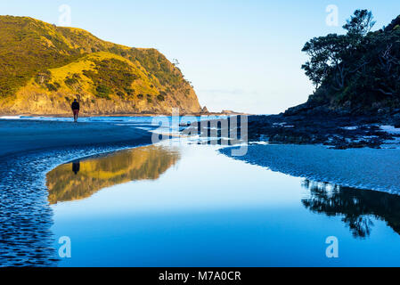 Man walking on beach where Tapotupotu Stream enters Tapotupotu Bay, near Cape Reinga, North Island, New Zealand Stock Photo