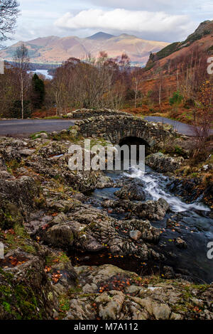 Historical Ashness Bridge, Lake District, England with stream, lake and mountains in autumn Stock Photo