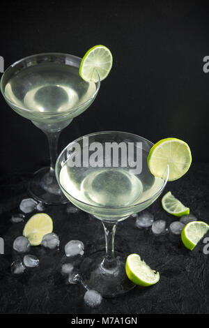 Margarita Сocktail with lime and ice on black stone table, copy space. Classic Margarita Cocktail. Stock Photo