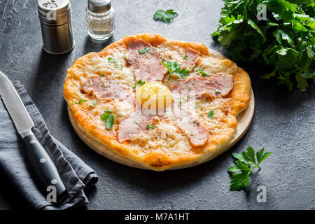 Pizza Carbonara on black stone background. Italian Pizza Carbonara with Bacon, Egg and Cheese, copy space. Stock Photo